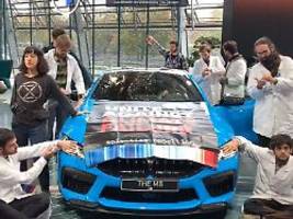 Protest in Münchener Showroom: Klima-Aktivisten kleben sich an BMW-Auto fest