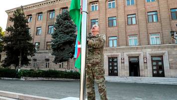 machtbeweis nach eroberung - aliyev hisst flagge in umkämpftem berg-karabach