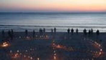1. mai: peace-zeichen: sylter erleuchten strand mit fackeln