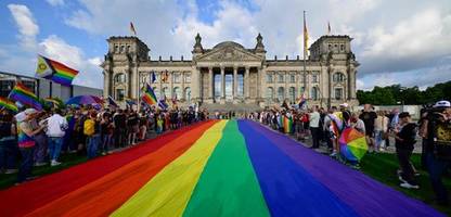 berlin: csd-teilnehmende protestieren mit riesiger regenbogenflagge vor reichstag
