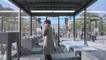 gläserne zelle vor rotem rathaus – das steckt dahinter